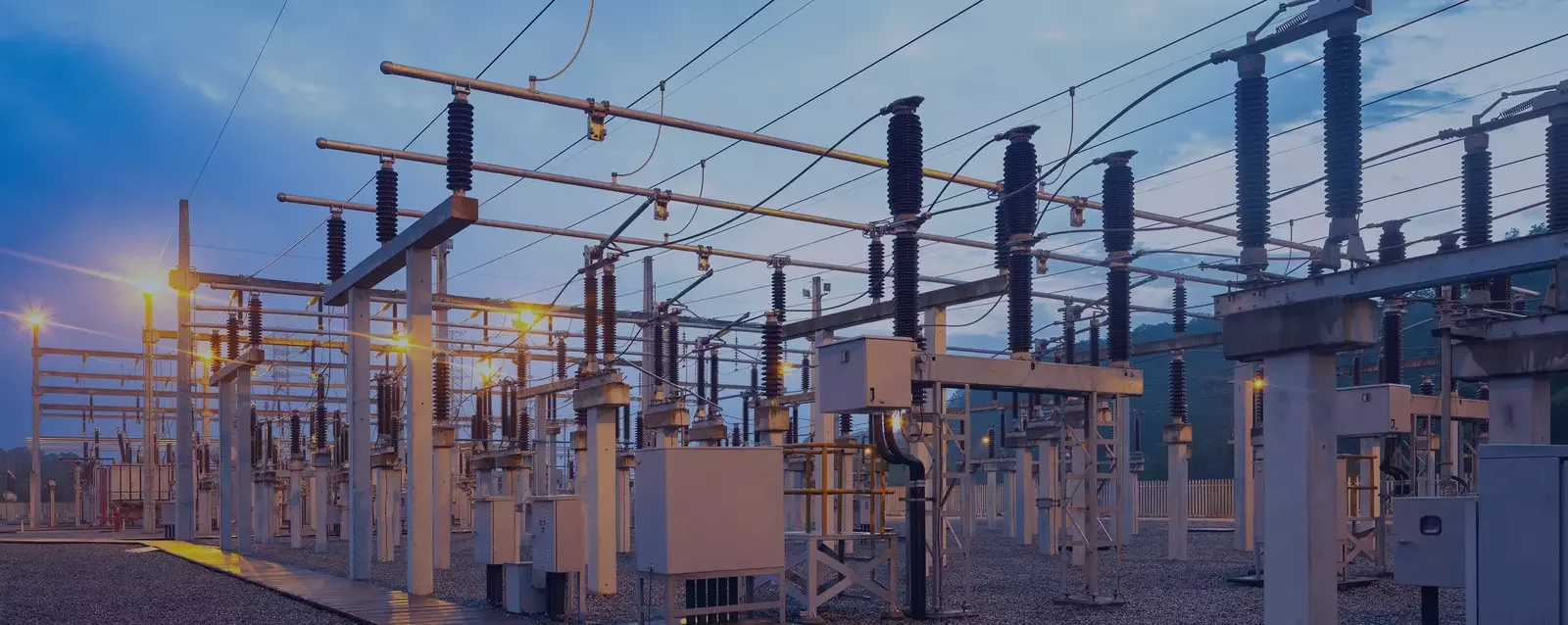 Electrical substation with transformers, switchgear, and overhead lines at dusk